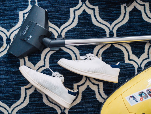 white shoes next to vacuum cleaner on rug