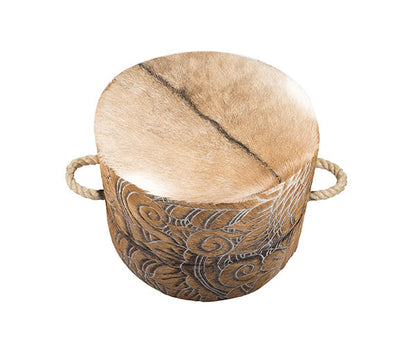 cowhide ottoman with intricate, etched floral and swirl pattern in tan and cream. It includes side tabs with thick, natural rope handles.