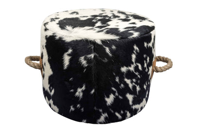 round cowhide ottoman with a natural black and white spotted pattern and tan leather tabs on the sides with thick, jute handles