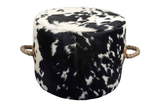 round cowhide ottoman with a natural black and white spotted pattern and tan leather tabs on the sides with thick, jute handles