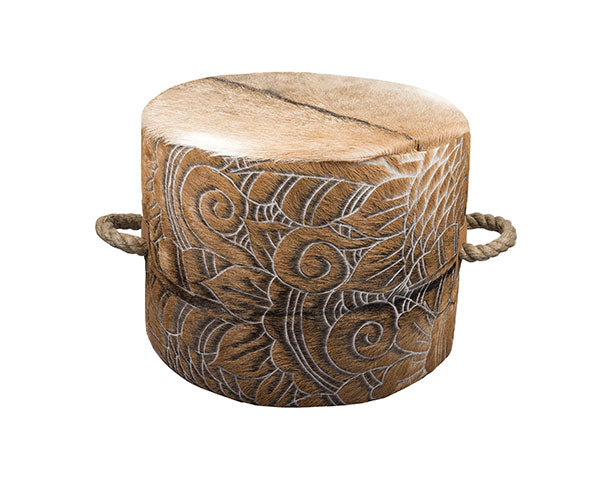 cowhide ottoman with intricate, etched floral and swirl pattern in tan and cream. It includes side tabs with thick, natural rope handles.